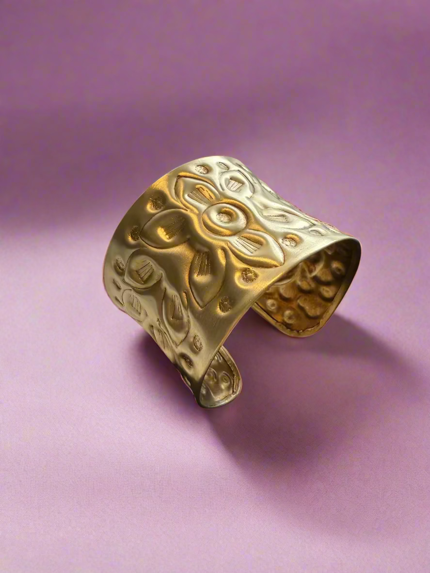 Gold cuff bracelet on a textured surface